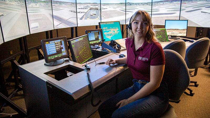 Female student sits in the cockpit of a flight simulator.